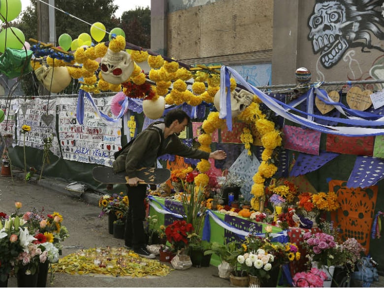 A man wafts incense smoke at a memorial to those who died in an art collective known as the Ghost Ship warehouse on the one year anniversary of the fire at the site Saturday, Dec. 2, 2017, in Oakland, Calif.